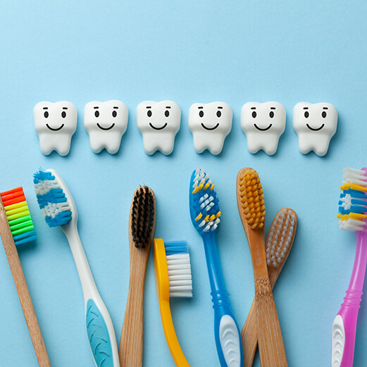 Row of animated teeth with smiley faces next to row of toothbrushes