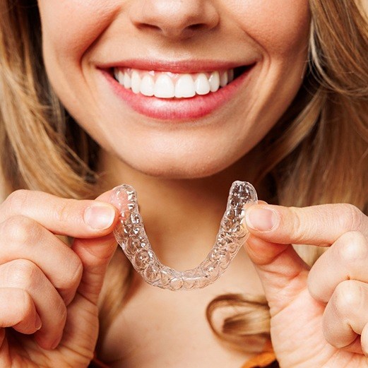 woman smiling with Invisalign tray 