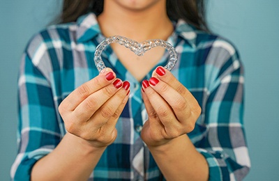 woman making a heart with Invisalign tray 
